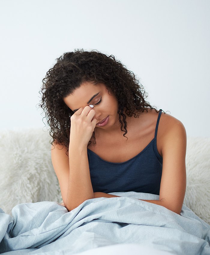 Exhausted woman sitting up in bed