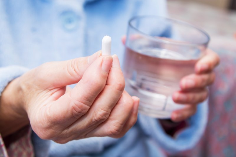 Older woman holding glass of water and sleeping pill