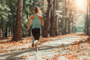 Woman jogging down trail through woods