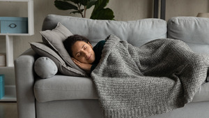 Woman taking nap on couch with blanket